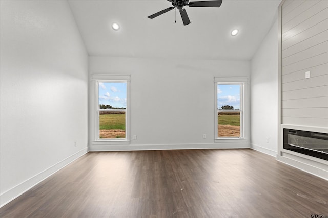 unfurnished living room with dark wood-type flooring, a wealth of natural light, vaulted ceiling, and ceiling fan