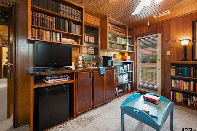 carpeted office space with wooden ceiling, ceiling fan, and wood walls