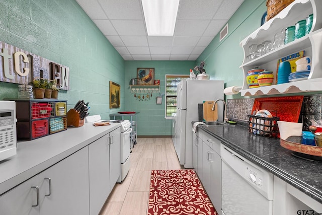 kitchen with white appliances, white cabinetry, and a paneled ceiling