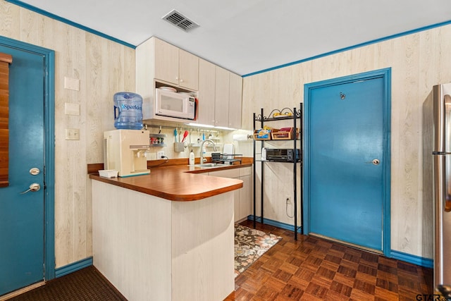 kitchen with dark parquet floors, stainless steel fridge, sink, and kitchen peninsula