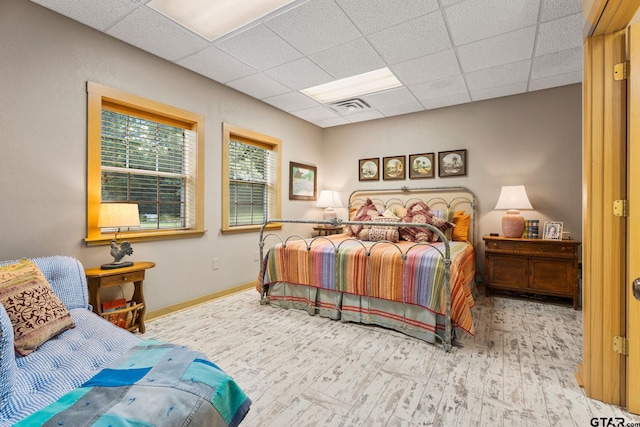 bedroom with a paneled ceiling and light hardwood / wood-style floors