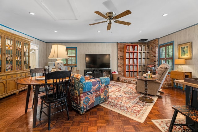 living room with dark parquet floors, ceiling fan, and crown molding