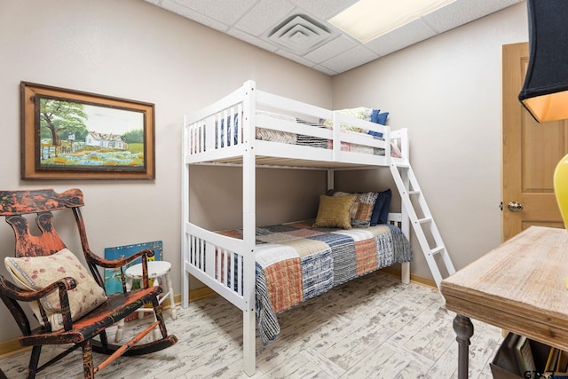 bedroom with a paneled ceiling and hardwood / wood-style floors