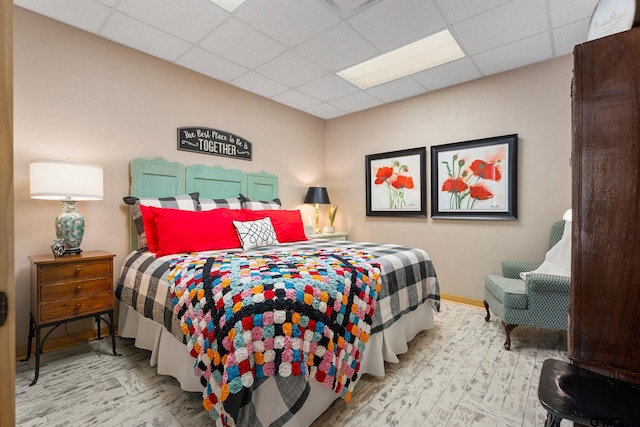 bedroom with a drop ceiling and light hardwood / wood-style floors