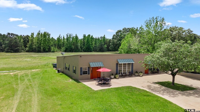 back of house with an outdoor fire pit, a yard, and a patio area