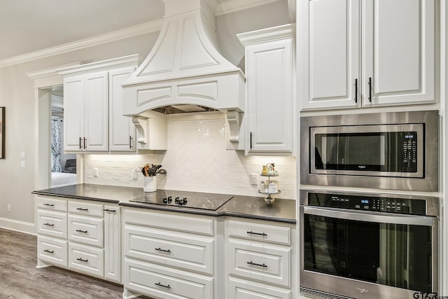 kitchen with white cabinets, premium range hood, appliances with stainless steel finishes, and ornamental molding