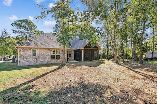 rear view of house featuring central air condition unit, a patio area, a lawn, and a sunroom