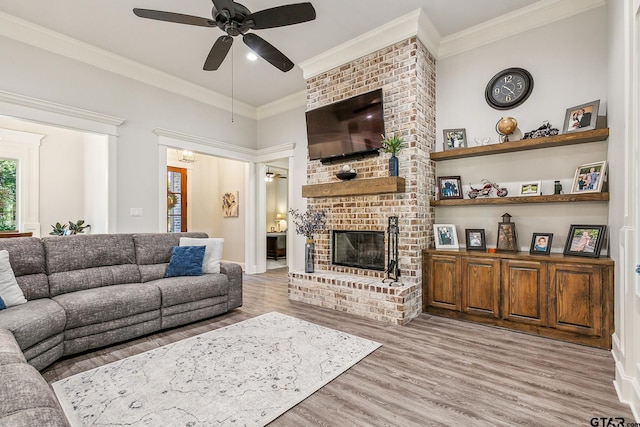 living room featuring ornamental molding, a fireplace, light hardwood / wood-style flooring, and ceiling fan