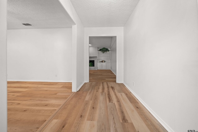 608 Meadow Crk, Tyler, TX 75703 - hallway featuring a textured ceiling and light wood-style flooring