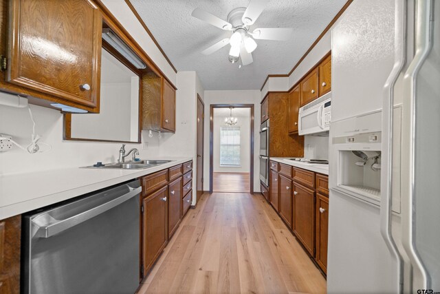 608 Meadow Crk, Tyler, TX 75703 - kitchen with appliances with stainless steel finishes, brown cabinetry, light countertops, light wood finished floors, and a textured ceiling