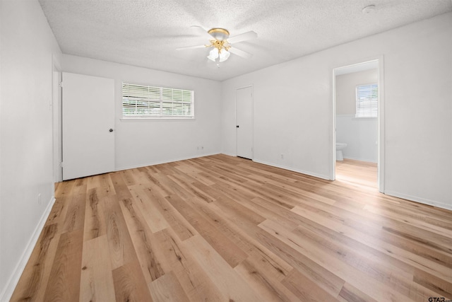 608 Meadow Crk, Tyler, TX 75703 - unfurnished bedroom with multiple windows, light wood-type flooring, a textured ceiling, ensuite bathroom, and ceiling fan