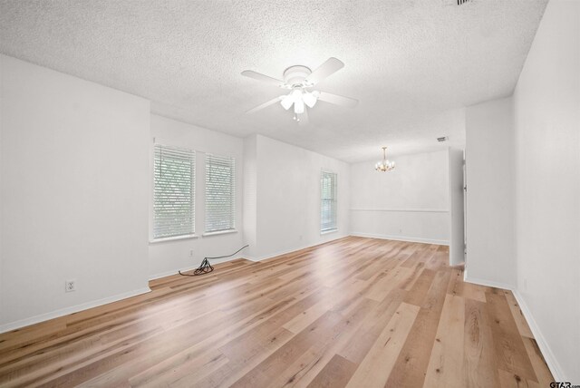 608 Meadow Crk, Tyler, TX 75703 - empty room featuring a chandelier, a ceiling fan, light wood-style flooring, and a textured ceiling