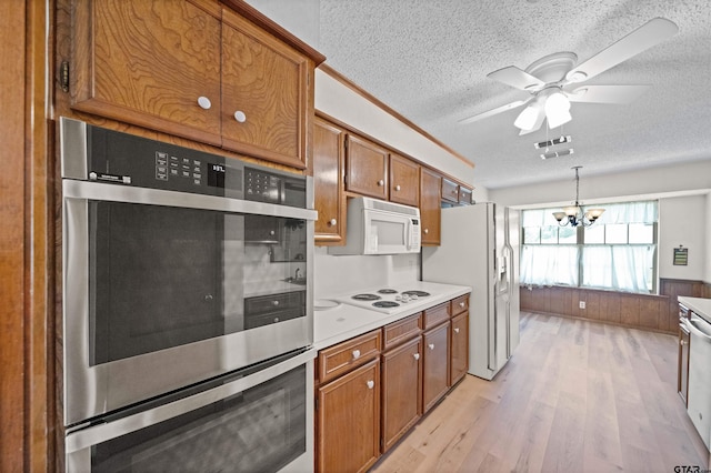 608 Meadow Crk, Tyler, TX 75703 - kitchen with white appliances, a textured ceiling, light wood-type flooring, brown cabinets, and light countertops