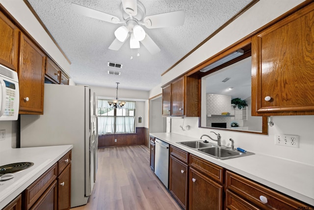 608 Meadow Crk, Tyler, TX 75703 - kitchen with white appliances, a textured ceiling, light countertops, light wood-style floors, and a chandelier