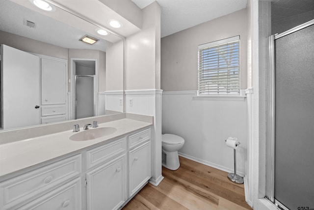 608 Meadow Crk, Tyler, TX 75703 - bathroom with a shower stall, vanity, wood finished floors, and a wainscoted wall