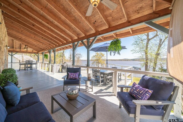 wooden terrace with outdoor lounge area, a water view, and a ceiling fan