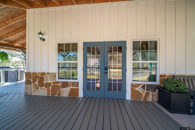 entrance to property featuring stone siding, a wooden deck, and french doors