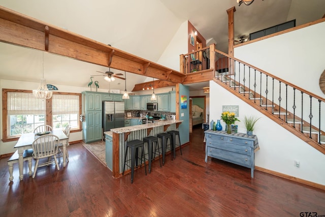 kitchen with green cabinets, a peninsula, stainless steel appliances, dark wood finished floors, and ceiling fan with notable chandelier