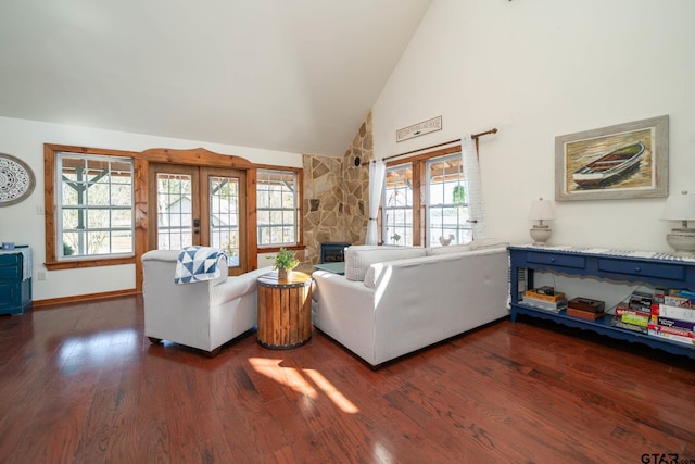 living room with dark wood finished floors, baseboards, a stone fireplace, and high vaulted ceiling
