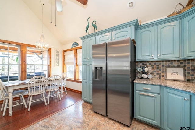 kitchen with backsplash, blue cabinets, stainless steel fridge, and ceiling fan with notable chandelier