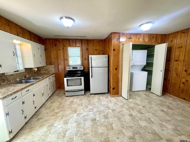 129 An County Rd 302, Frankston, TX 75763 - kitchen with appliances with stainless steel finishes, estacked washer and dryer, a sink, wood walls, and white cabinetry
