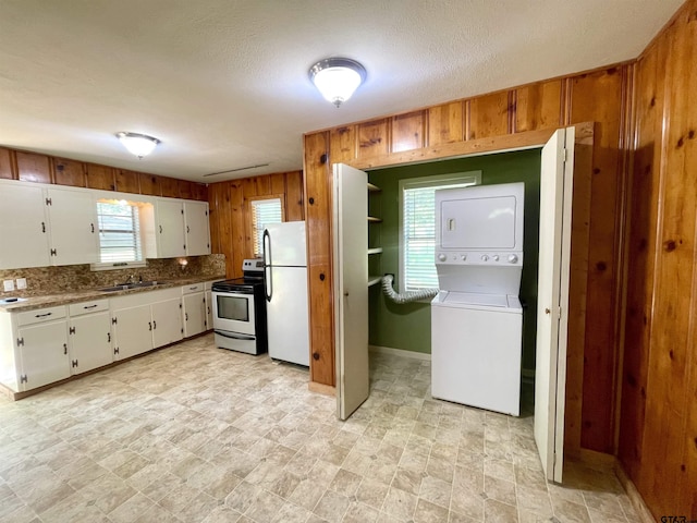 129 An County Rd 302, Frankston, TX 75763 - kitchen featuring freestanding refrigerator, stacked washing machine and dryer, stainless steel electric range, a sink, and wooden walls