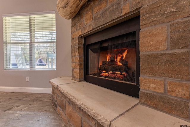 details with a stone fireplace and baseboards