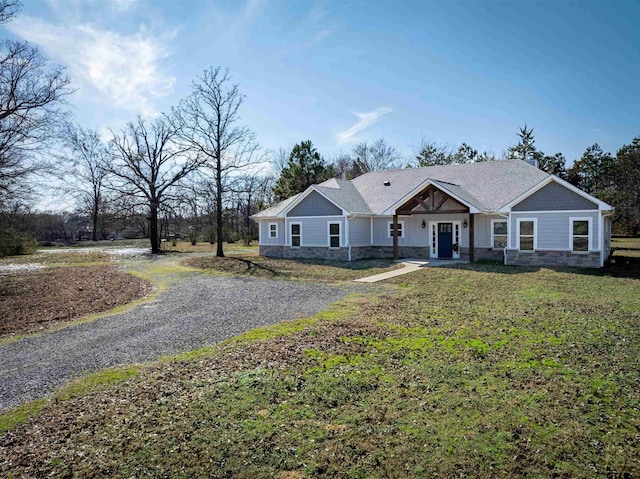 view of front of house with stone siding, roof with shingles, and a front lawn