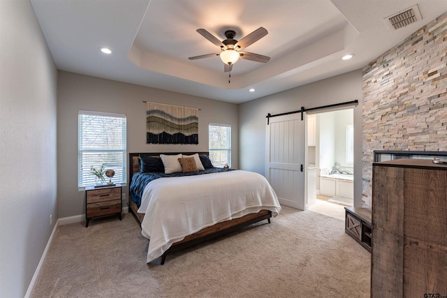 bedroom featuring a tray ceiling, a barn door, multiple windows, and visible vents