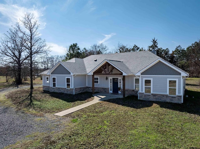 craftsman inspired home with stone siding, a front lawn, and roof with shingles