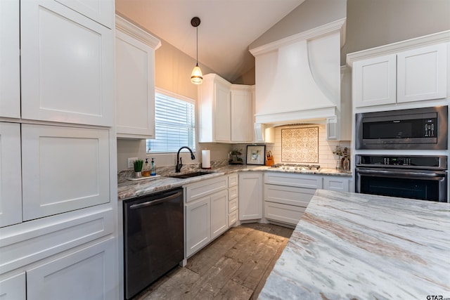 kitchen with decorative backsplash, lofted ceiling, black appliances, premium range hood, and a sink