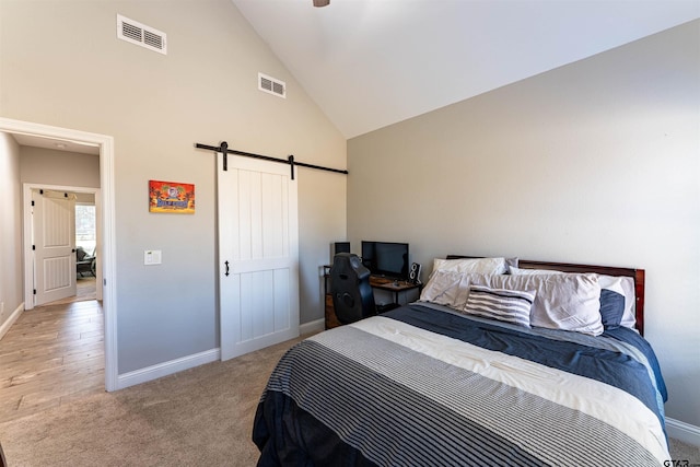 bedroom with high vaulted ceiling, a barn door, visible vents, and baseboards