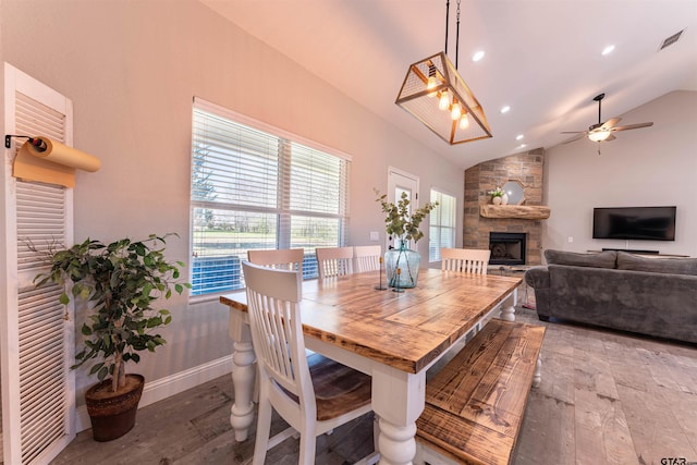 dining area featuring a fireplace, visible vents, baseboards, vaulted ceiling, and wood-type flooring