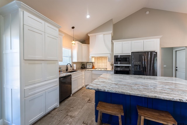 kitchen featuring stainless steel appliances, a breakfast bar, a sink, white cabinetry, and tasteful backsplash