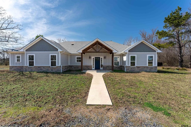 craftsman house with stone siding, a front lawn, board and batten siding, and roof with shingles