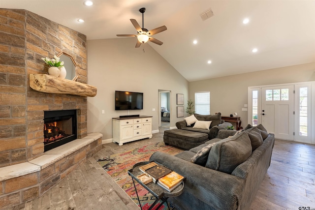 living area featuring high vaulted ceiling, a fireplace, wood-type flooring, and visible vents