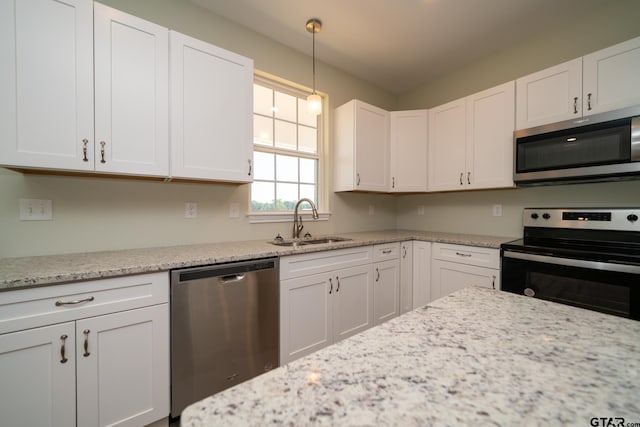 kitchen featuring white cabinetry, sink, appliances with stainless steel finishes, light stone countertops, and pendant lighting