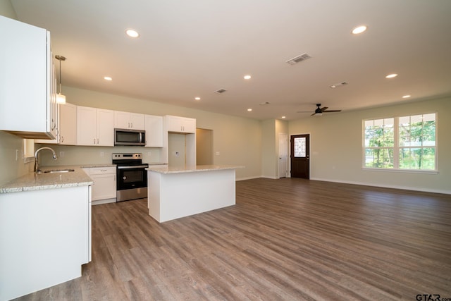 kitchen with stainless steel appliances, white cabinetry, dark hardwood / wood-style flooring, sink, and a center island