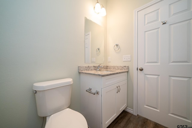 bathroom featuring toilet, vanity, and hardwood / wood-style floors