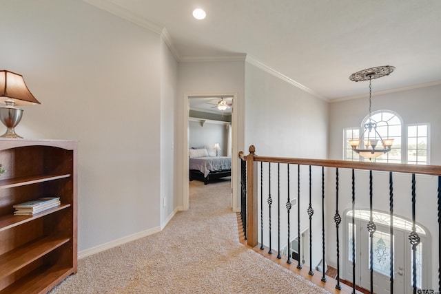 corridor with a chandelier, crown molding, and light colored carpet