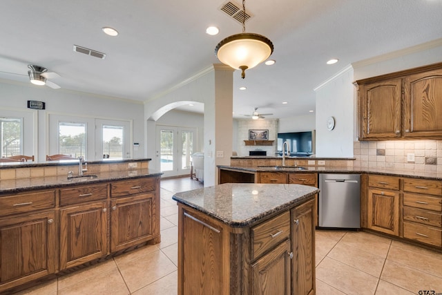 kitchen with dark stone counters, stainless steel dishwasher, french doors, and plenty of natural light