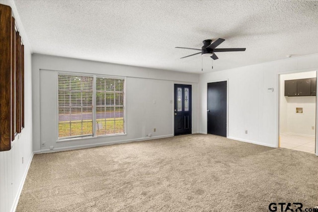 empty room with carpet flooring, a textured ceiling, ceiling fan, and baseboards