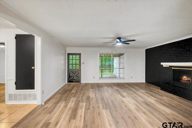 unfurnished living room with light wood-type flooring, ornamental molding, and a brick fireplace