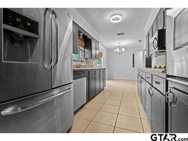 526 Ronnette Dr, Tyler, TX 75703 - kitchen featuring appliances with stainless steel finishes, tasteful backsplash, a chandelier, a textured ceiling, and light tile patterned flooring