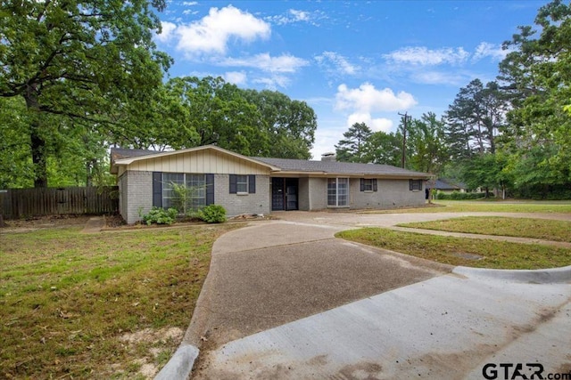 ranch-style home featuring a chimney, a front yard, brick siding, fence, and concrete driveway