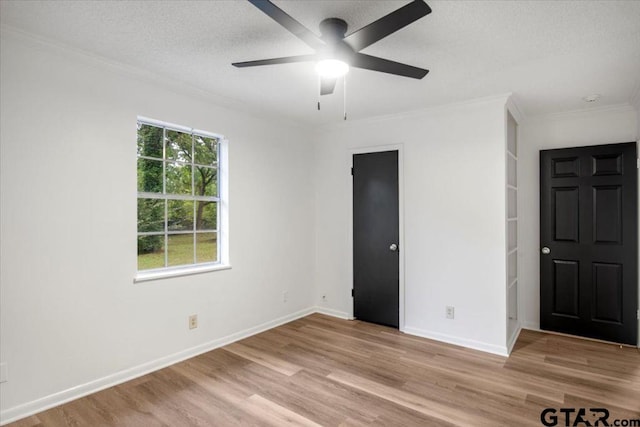 unfurnished bedroom with crown molding, ceiling fan, light wood finished floors, a textured ceiling, and baseboards