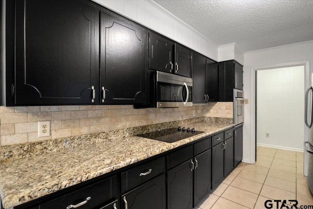 kitchen with dark cabinetry, a textured ceiling, stainless steel appliances, decorative backsplash, and light tile patterned floors