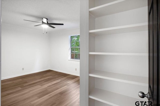 spare room with baseboards, a ceiling fan, a textured ceiling, and wood finished floors