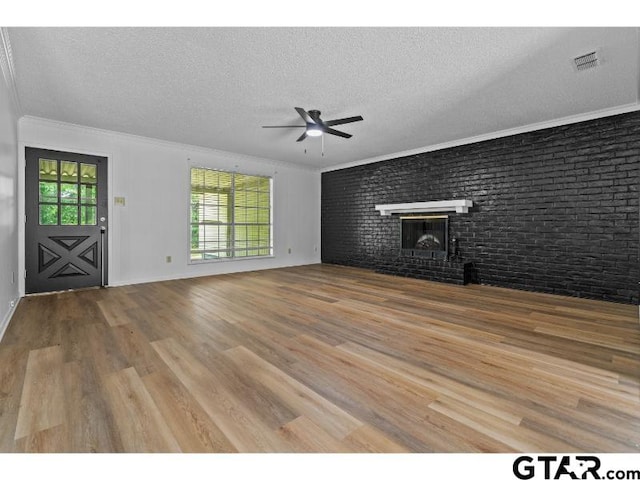 526 Ronnette Dr, Tyler, TX 75703 - unfurnished living room with ceiling fan, ornamental molding, wood finished floors, a textured ceiling, and a brick fireplace