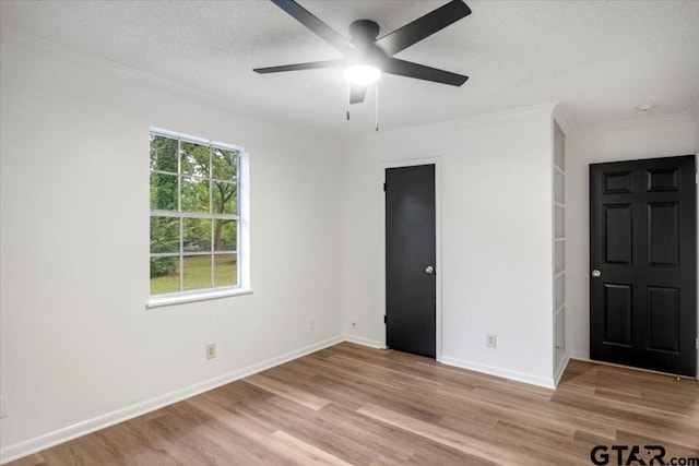 unfurnished bedroom with ornamental molding, wood finished floors, baseboards, ceiling fan, and a textured ceiling